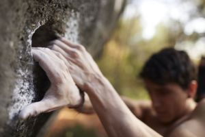 Young man performing rock climbing hold.